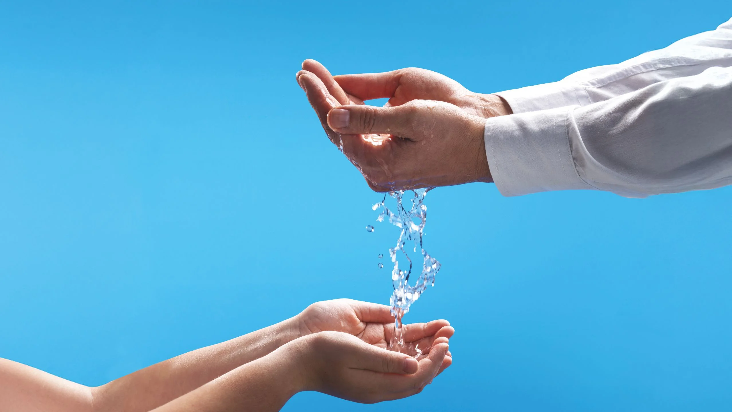 mano bambino e adulto con acqua: campagna sostelia